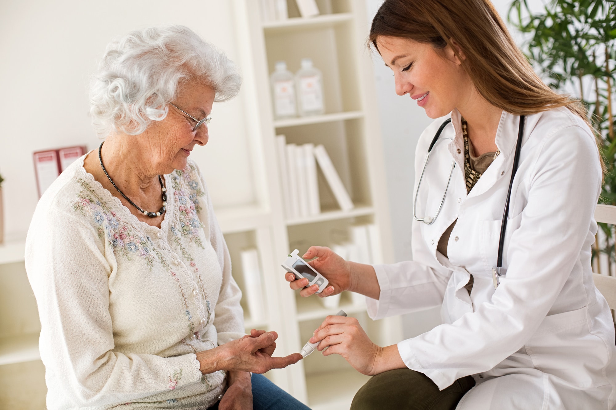 Young female doctor making diabetes blood test on senior woman, closeup