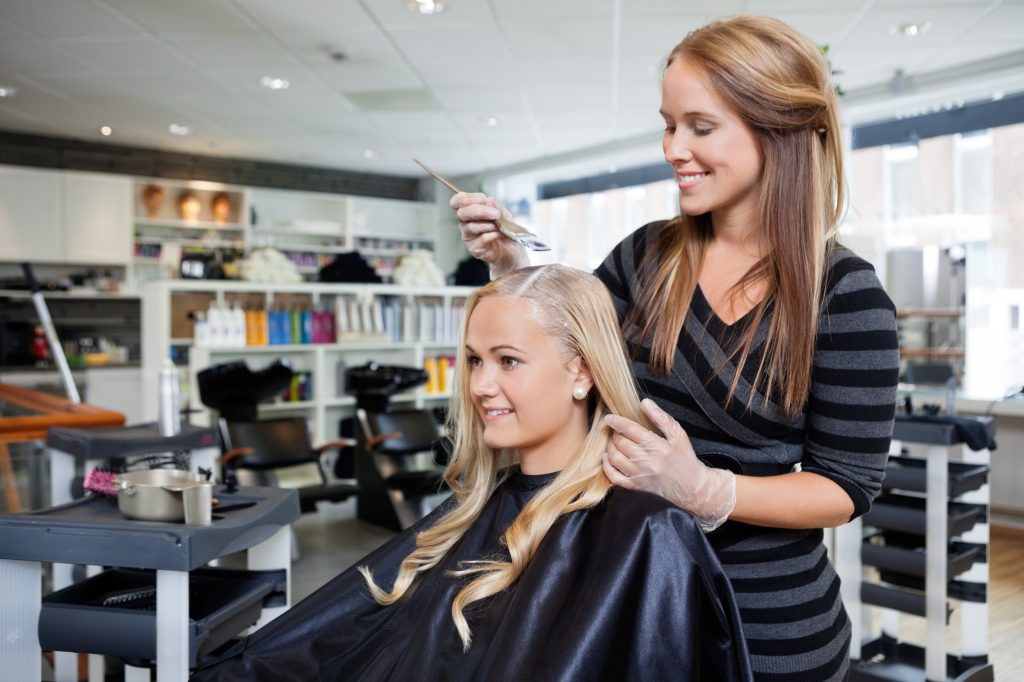 Young woman having her hair dyed by beautician at parlor